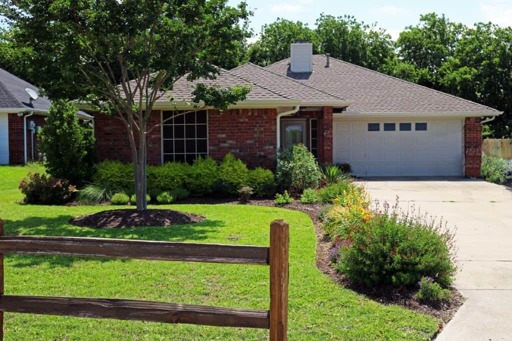 Single-story brick house with attached two-car garage and manicured front yard — Tarrant County landscape project by Ellis Landscape Services